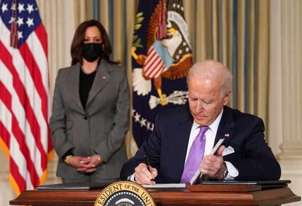 US Presideng Joe Biden signing the deal and vice president kamala behind US Presideng Joe Biden signing the deal and vice president kamala behind